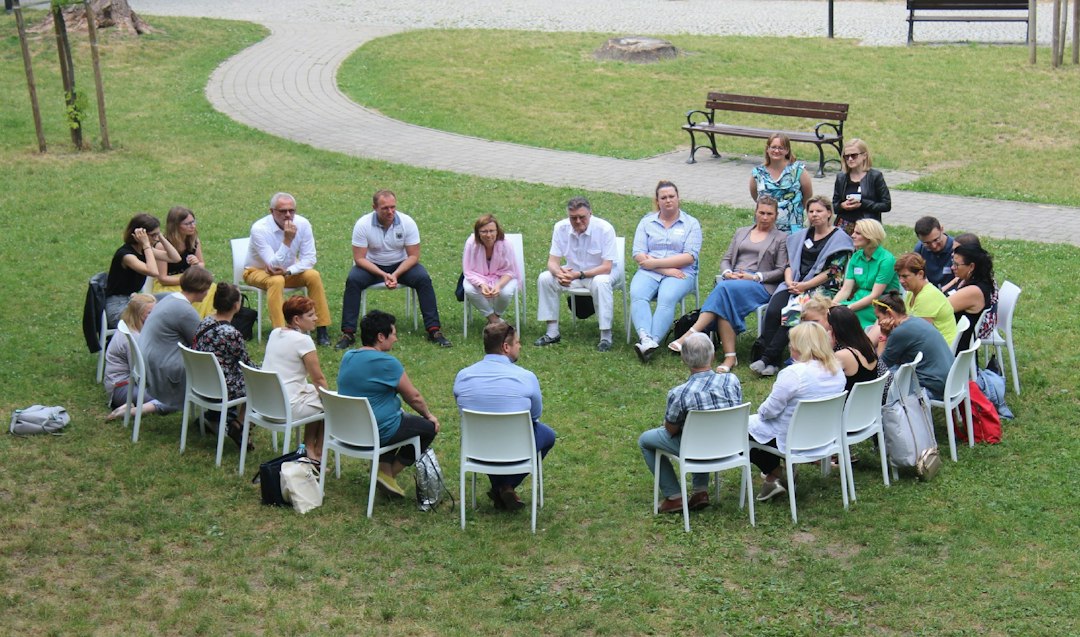 People gathered in an outdoor circle, illustrating community support and social work-related roles